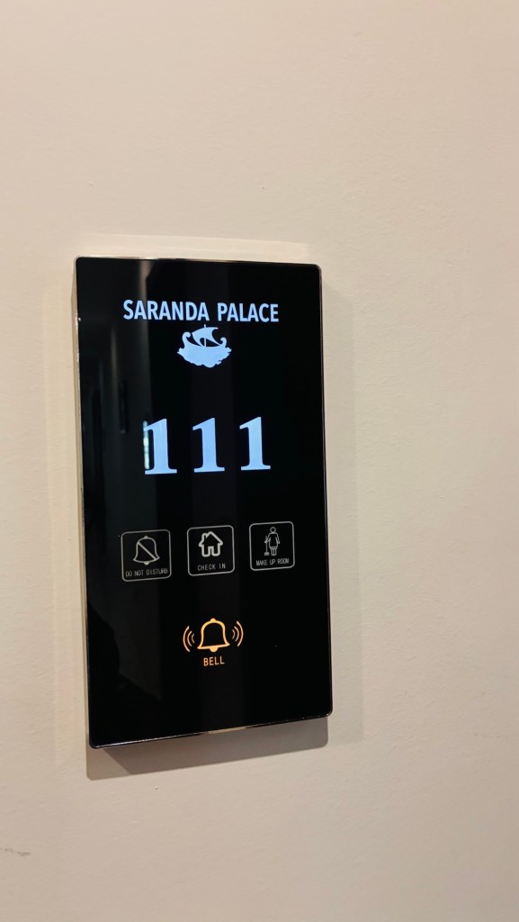 Panneau de chambre d'hôtel au Saranda Palace marquant le numéro 111, avec des boutons pour 'ne pas déranger', 'enregistrement', et 'faire la chambre'.