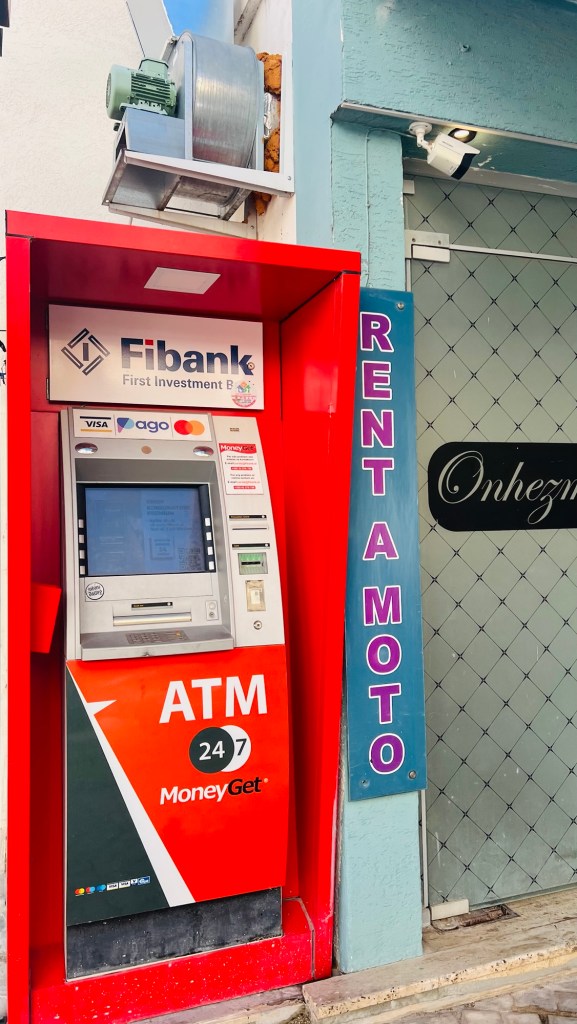 Distributeur automatique de billets Fibank situé à côté d'une enseigne de location de motos.